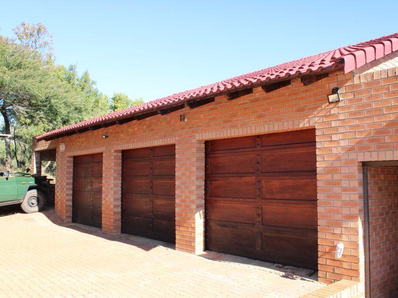 A triple garage featuring face brick construction, wooden garage doors, and a tiled roof, situated on a paved driveway.