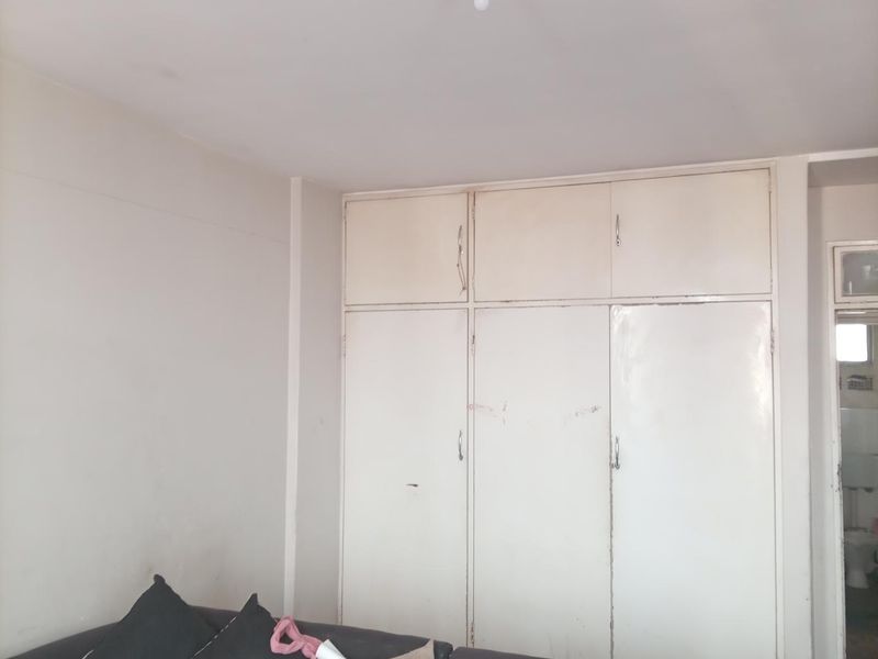 A bedroom featuring a built-in wardrobe with white cabinetry, requiring minor cosmetic updates to the wall finishes and wardrobe doors.