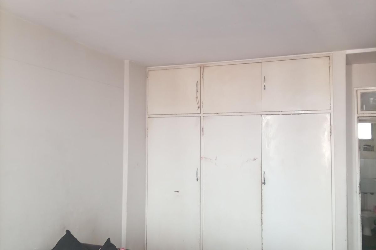 A bedroom featuring a built-in wardrobe with white cabinetry, requiring minor cosmetic updates to the wall finishes and wardrobe doors.