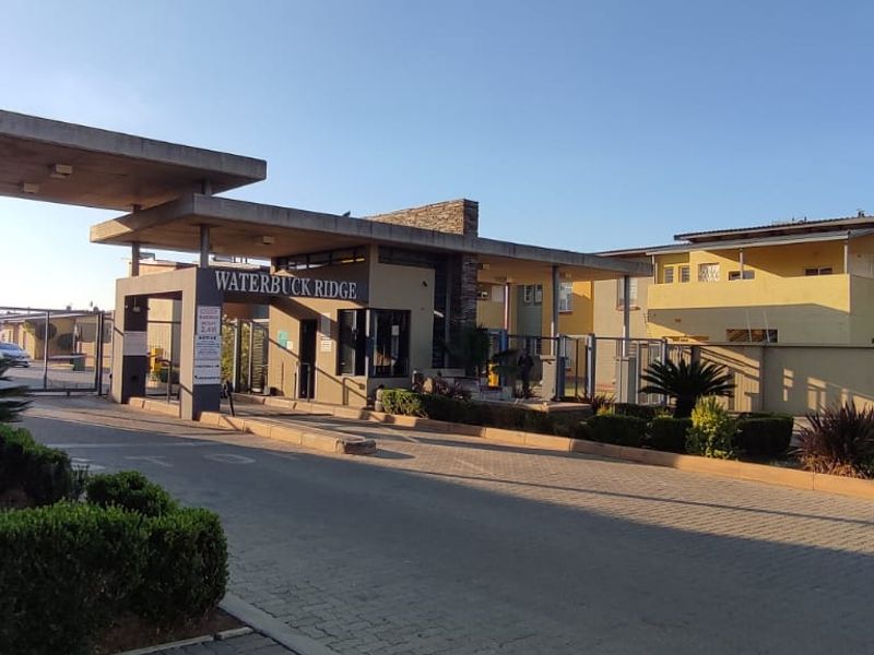 The main entrance and security gatehouse of Waterbuck Ridge townhouse complex, featuring paved access and established perimeter security.