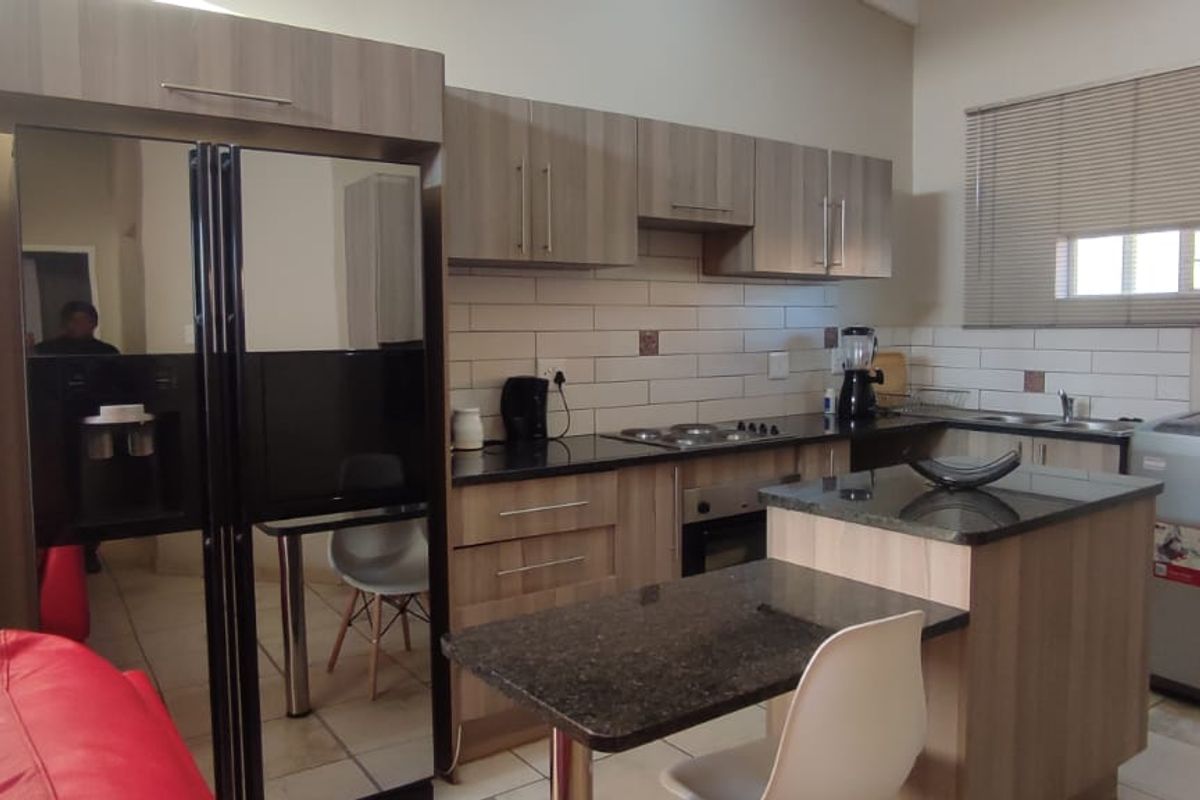 A functional kitchen featuring wood-finish cabinetry, granite countertops, a central island, and a subway tile backsplash, providing a practical and modern cooking space.