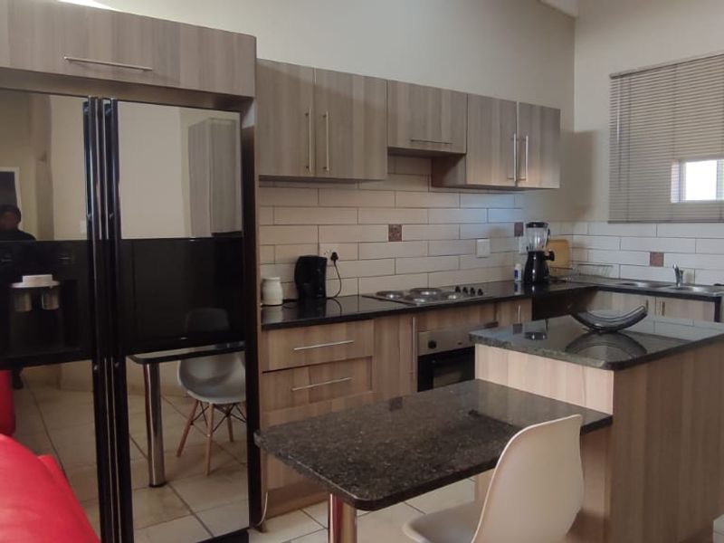 A functional kitchen featuring wood-finish cabinetry, granite countertops, a central island, and a subway tile backsplash, providing a practical and modern cooking space.