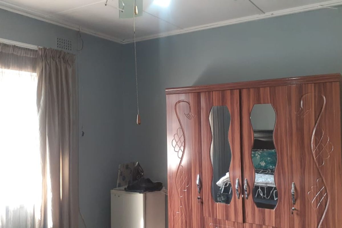 A bedroom featuring neutral wall tones, a window with curtains, and a ceiling light fixture.