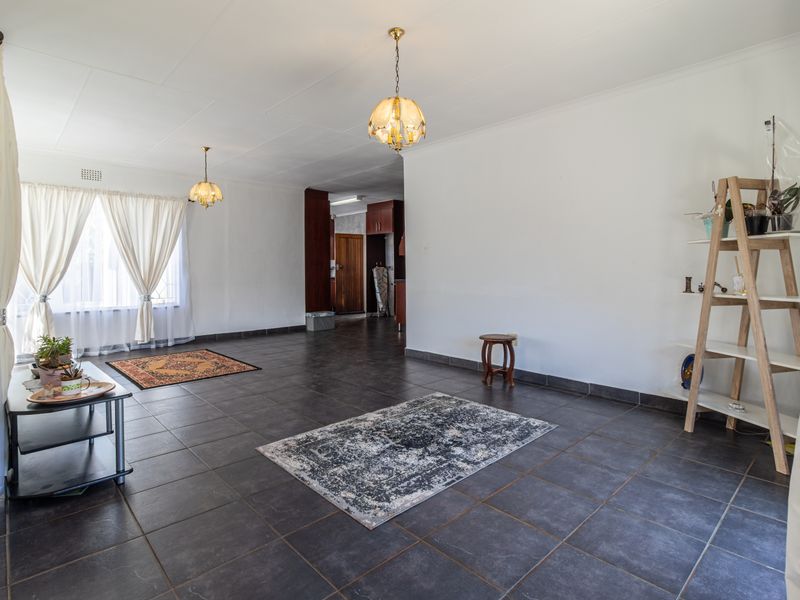 Spacious living area featuring dark floor tiles, coved ceilings, and pendant lighting, offering a neutral blank canvas for interior design.