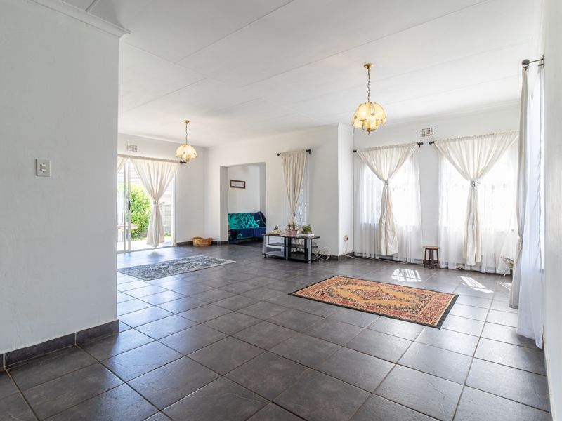 Spacious, light-filled living area featuring neutral tiled flooring, coved ceilings, and large sliding glass doors providing access to the outdoor space.