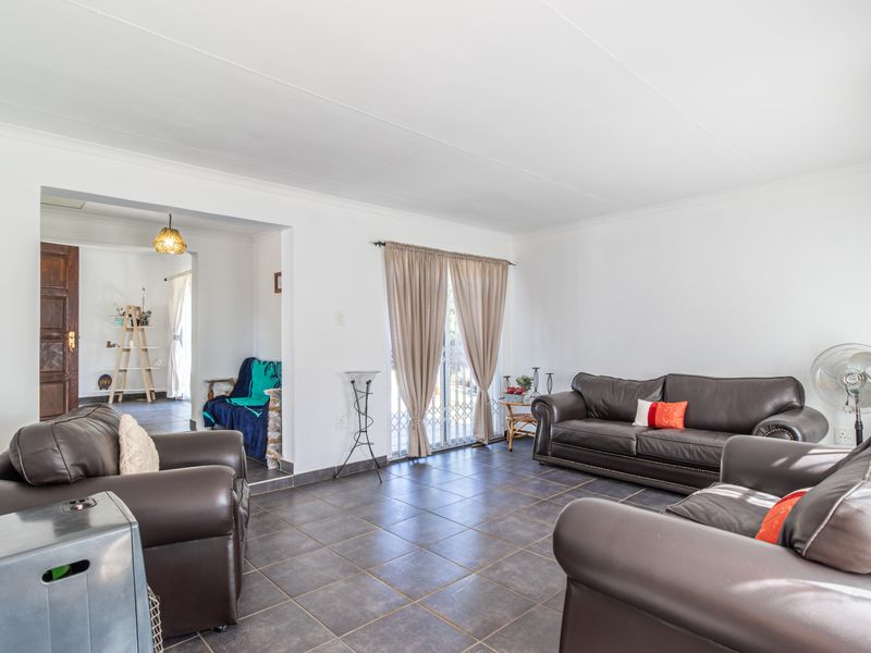 Spacious living room featuring dark tiled flooring, neutral walls, and a sliding glass door providing access to the exterior.
