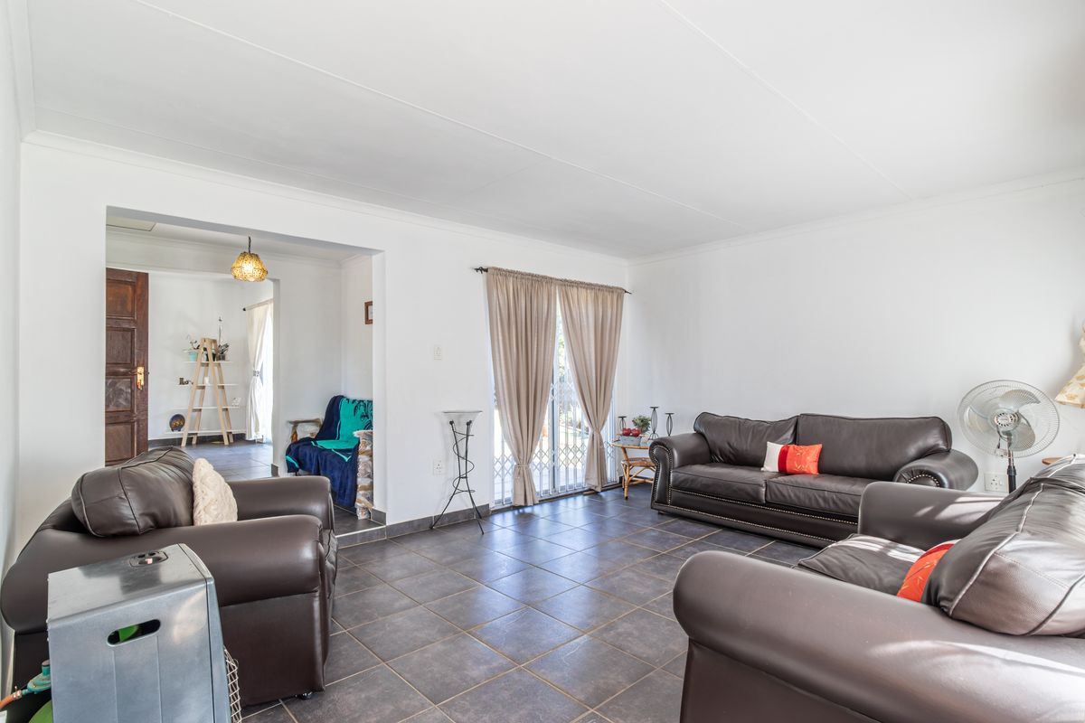 Spacious living room featuring dark tiled flooring, neutral walls, and a sliding glass door providing access to the exterior.
