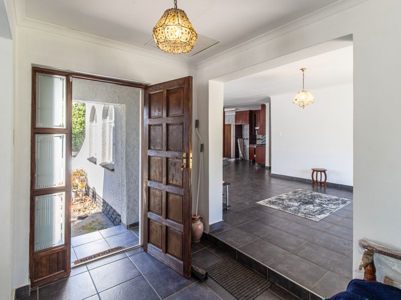 Welcoming entrance hall featuring tiled flooring and a solid wood panel door, leading into an open-plan living area with neutral finishes.