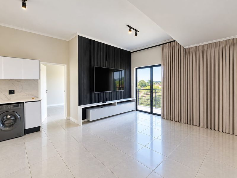 Modern open-plan living area featuring sleek tiled floors, a striking black slatted feature wall, and direct access to a balcony through sliding glass doors.