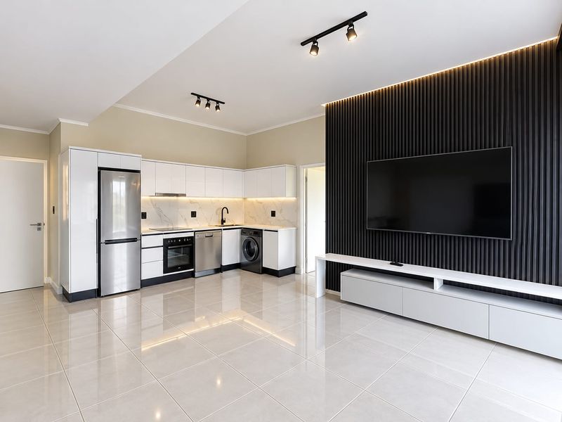 Modern open-plan living area featuring a sleek kitchen with integrated appliances, high-gloss cabinetry, and a striking black slatted feature wall with ambient lighting.
