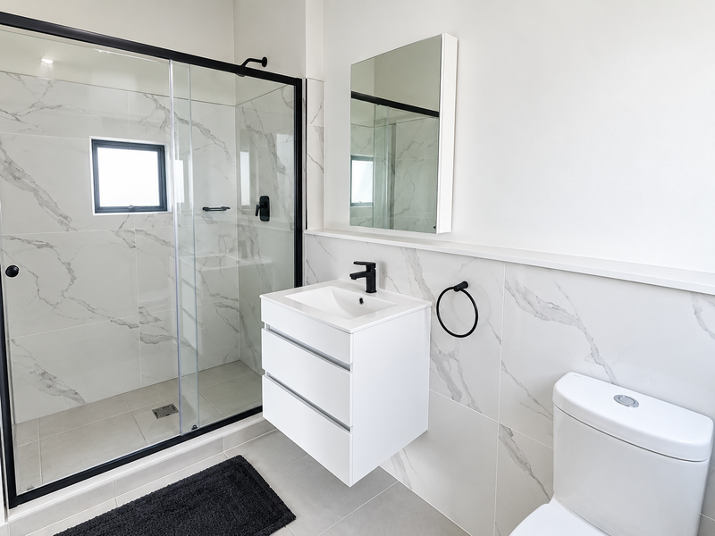 Modern bathroom featuring a walk-in shower with glass enclosure, wall-mounted vanity with black fixtures, and elegant marble-look wall tiling.