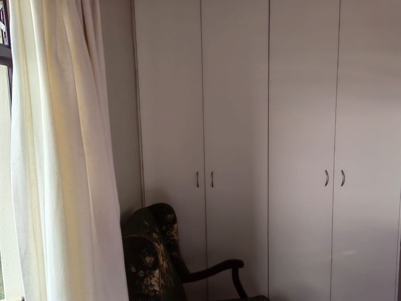 A bedroom featuring floor-to-ceiling built-in cupboards with white doors, providing ample storage space.