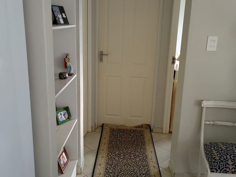 A functional hallway featuring built-in shelving units and tiled flooring, providing access to adjacent rooms through internal doors.