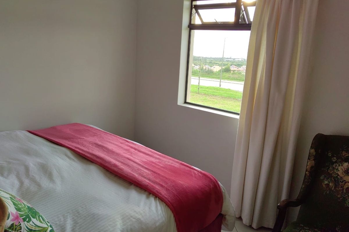 A bedroom featuring tiled flooring and a top-hung window with views of the surrounding area.