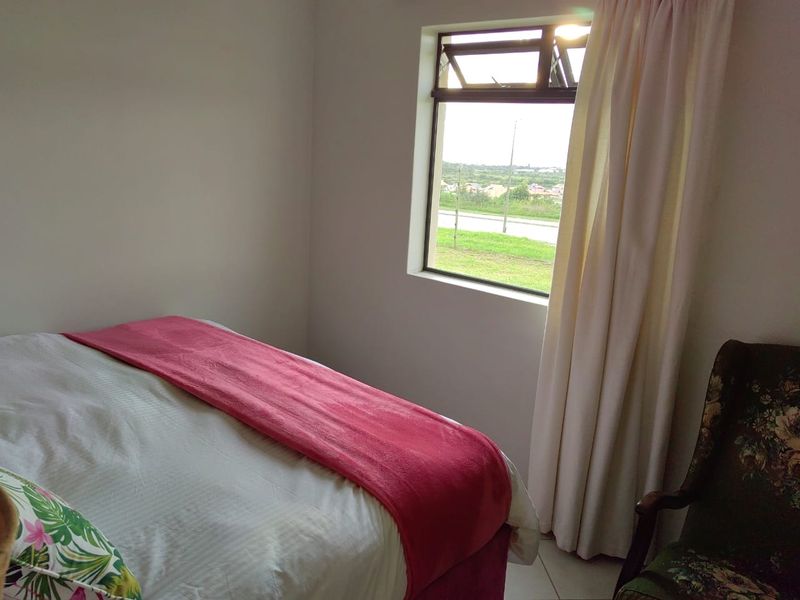 A bedroom featuring tiled flooring and a top-hung window with views of the surrounding area.