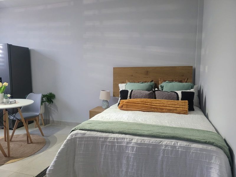 A well-maintained bedroom featuring tiled flooring and a modern slatted timber headboard, offering a clean and functional living space.