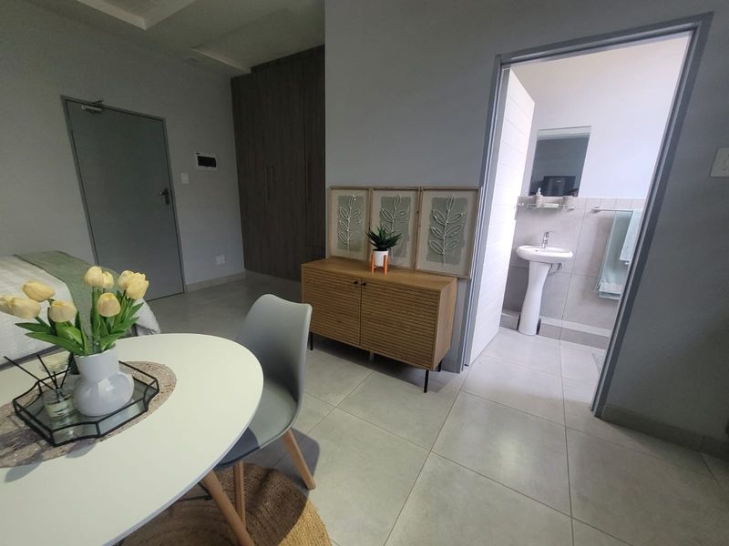 A well-maintained bedroom featuring tiled flooring, built-in cupboards, and an en-suite bathroom with a pedestal basin.