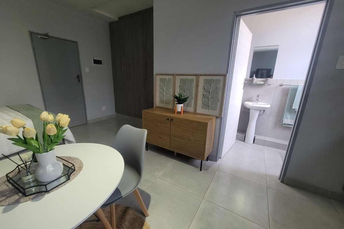 A well-maintained bedroom featuring tiled flooring, built-in cupboards, and an en-suite bathroom with a pedestal basin.