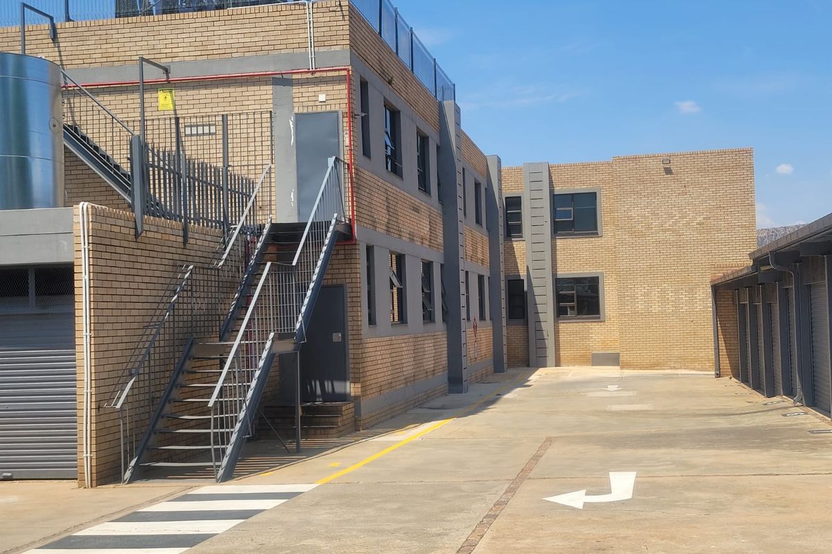 Exterior view of the apartment complex featuring face brick construction, external metal staircases, a concrete driveway, and integrated garage units.
