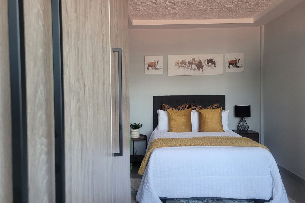 A well-maintained bedroom featuring a built-in wardrobe with wood-grain finish and a textured ceiling.