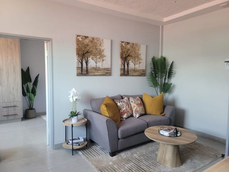 A well-maintained living room featuring neutral wall tones, tiled flooring, and a modern recessed ceiling detail, creating a bright and inviting atmosphere.