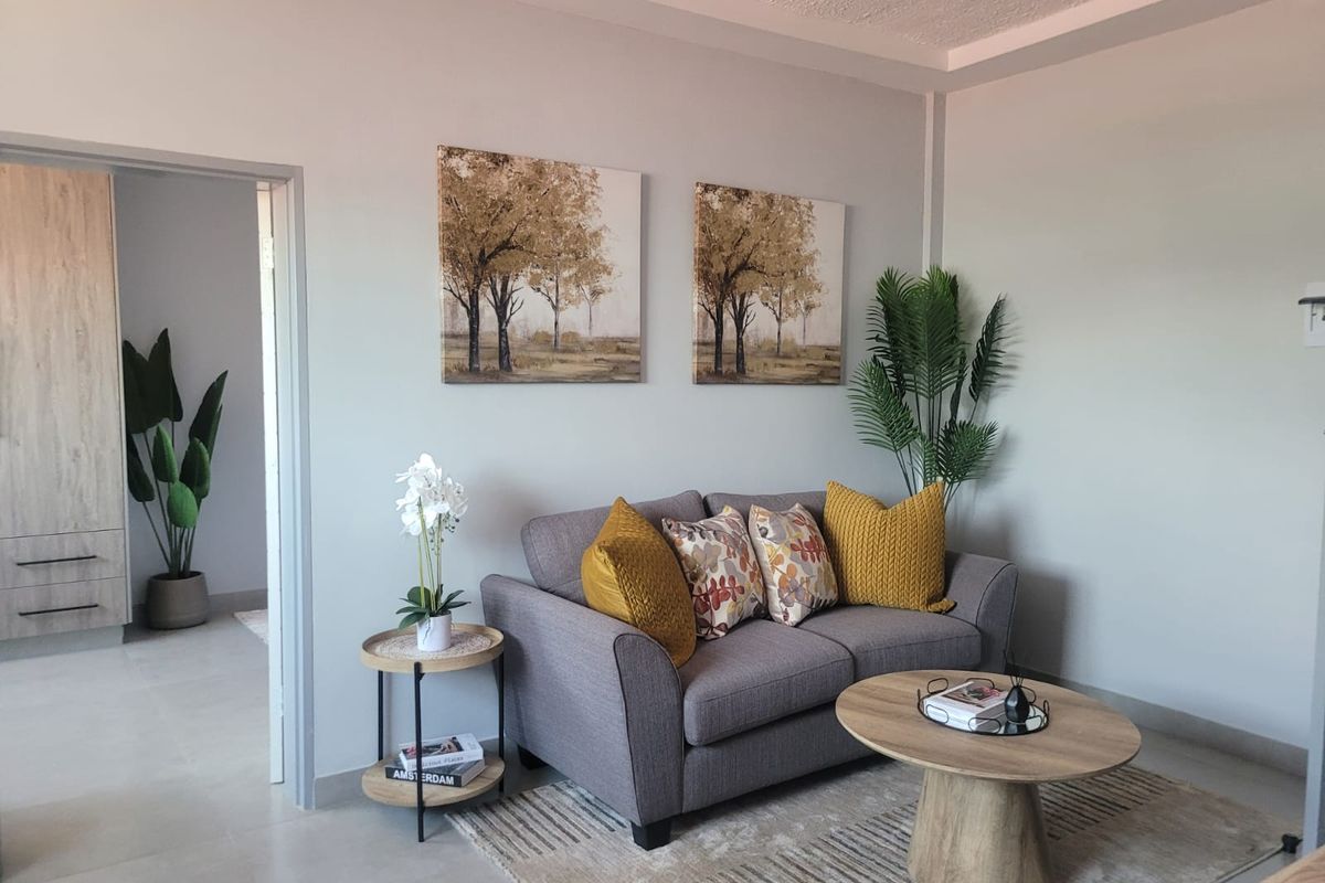 A well-maintained living room featuring neutral wall tones, tiled flooring, and a modern recessed ceiling detail, creating a bright and inviting atmosphere.