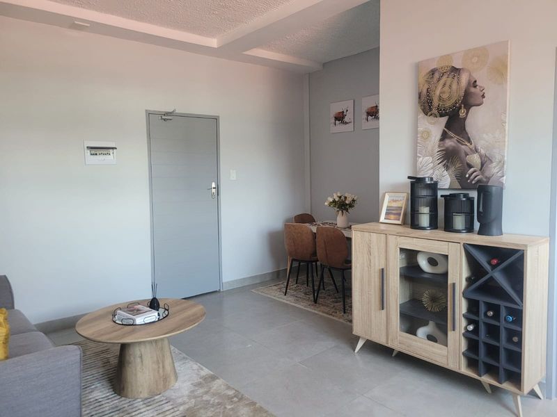 An open-plan living and dining area featuring neutral tiled flooring and a clean, modern aesthetic with a functional layout.
