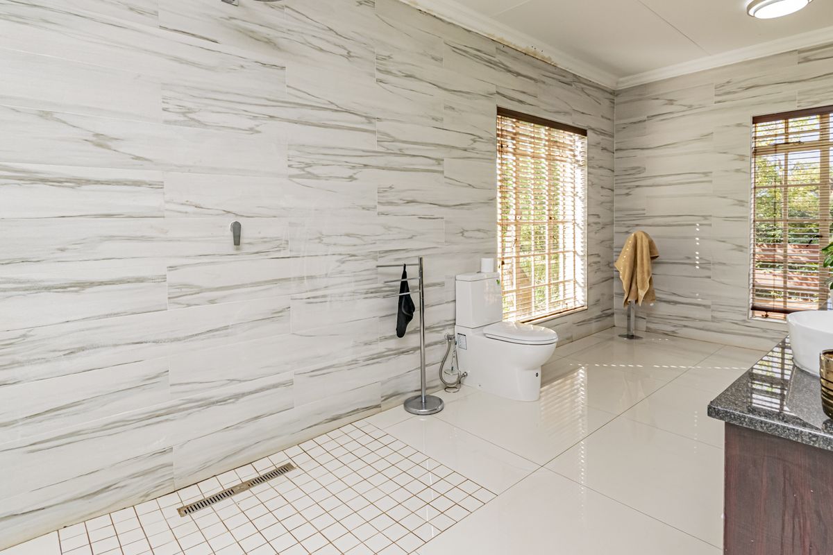 Modern bathroom featuring marble-look wall tiling, a spacious walk-in shower with a linear drain, and a vanity unit.