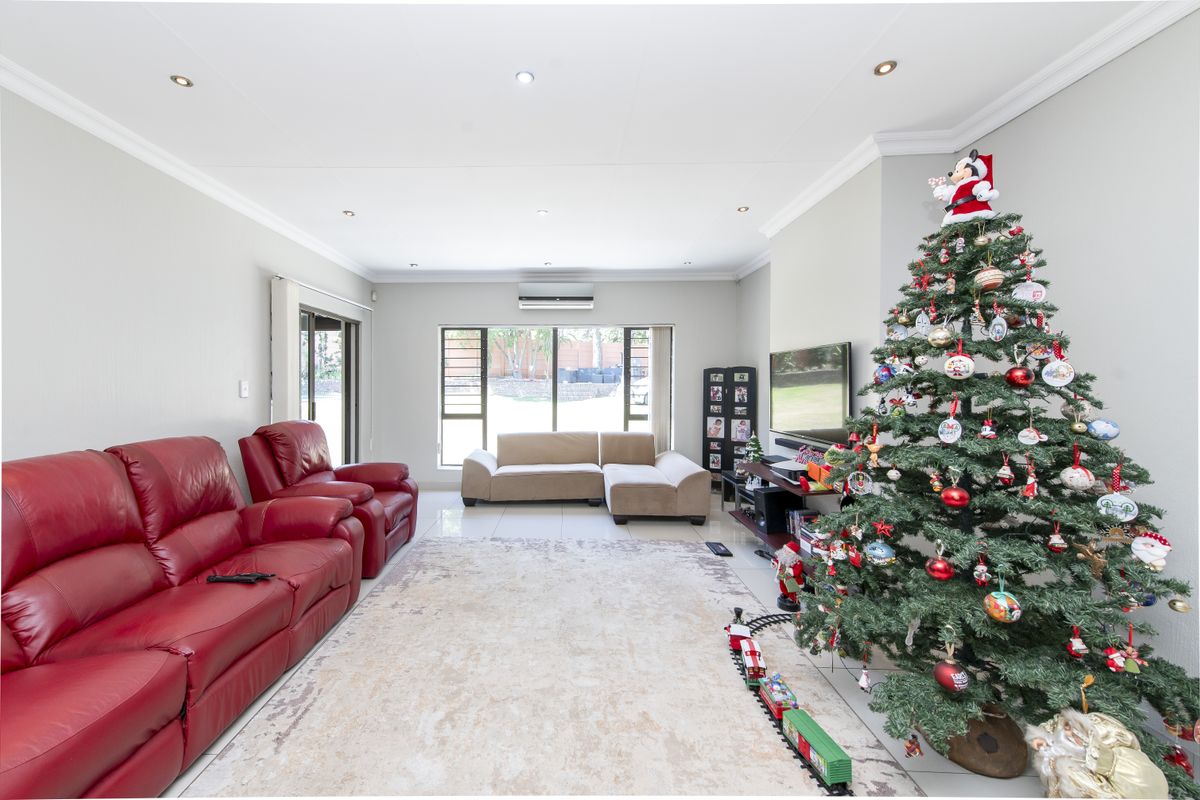 Spacious living room featuring tiled flooring, recessed downlighting, and a wall-mounted air conditioning unit, providing a comfortable and well-lit living space.
