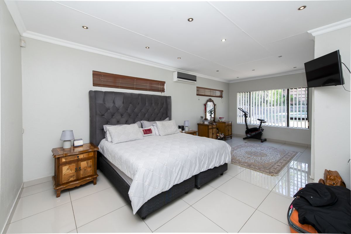 Spacious bedroom featuring tiled flooring, recessed ceiling lighting, and a wall-mounted air conditioning unit.