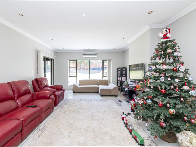 Spacious living room featuring tiled flooring, recessed downlighting, and a wall-mounted air conditioning unit, providing a comfortable and well-lit living space.