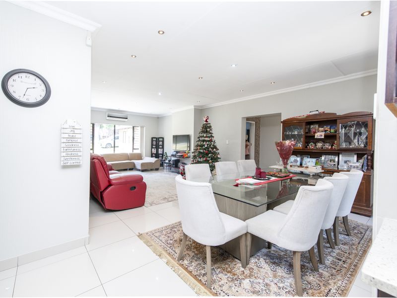 An open-plan living and dining area featuring tiled flooring, recessed downlighting, and a wall-mounted air conditioning unit.