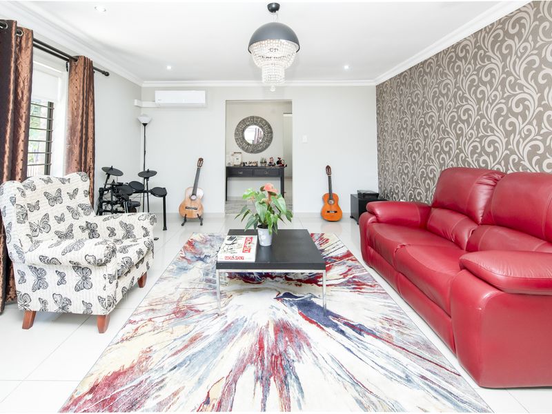 A bright living room featuring tiled flooring, a decorative feature wall, and a wall-mounted air conditioning unit.