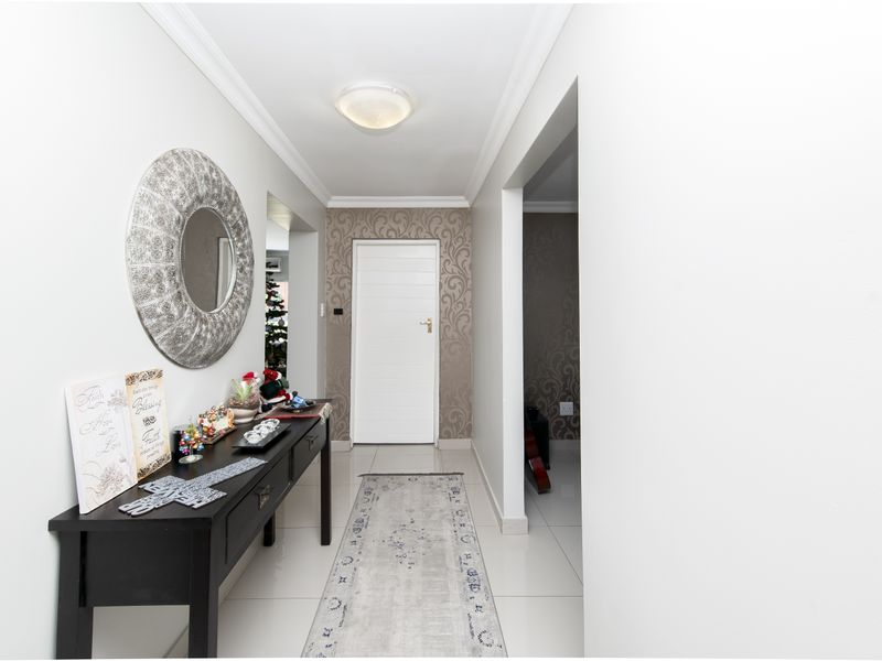 A bright and welcoming entrance hallway featuring tiled flooring, decorative wallpaper accents, and a clean, modern aesthetic.
