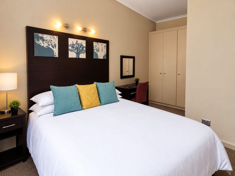 A well-maintained bedroom featuring a built-in wardrobe, neutral wall tones, and carpeted flooring, providing a comfortable and functional living space.