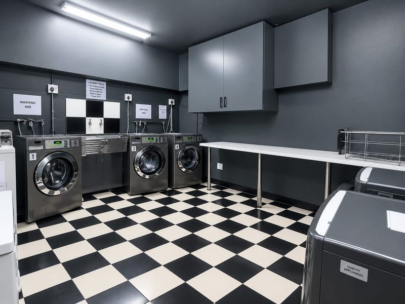 A well-maintained communal laundry facility featuring multiple washing machines, built-in cabinetry, and a durable checkered floor.