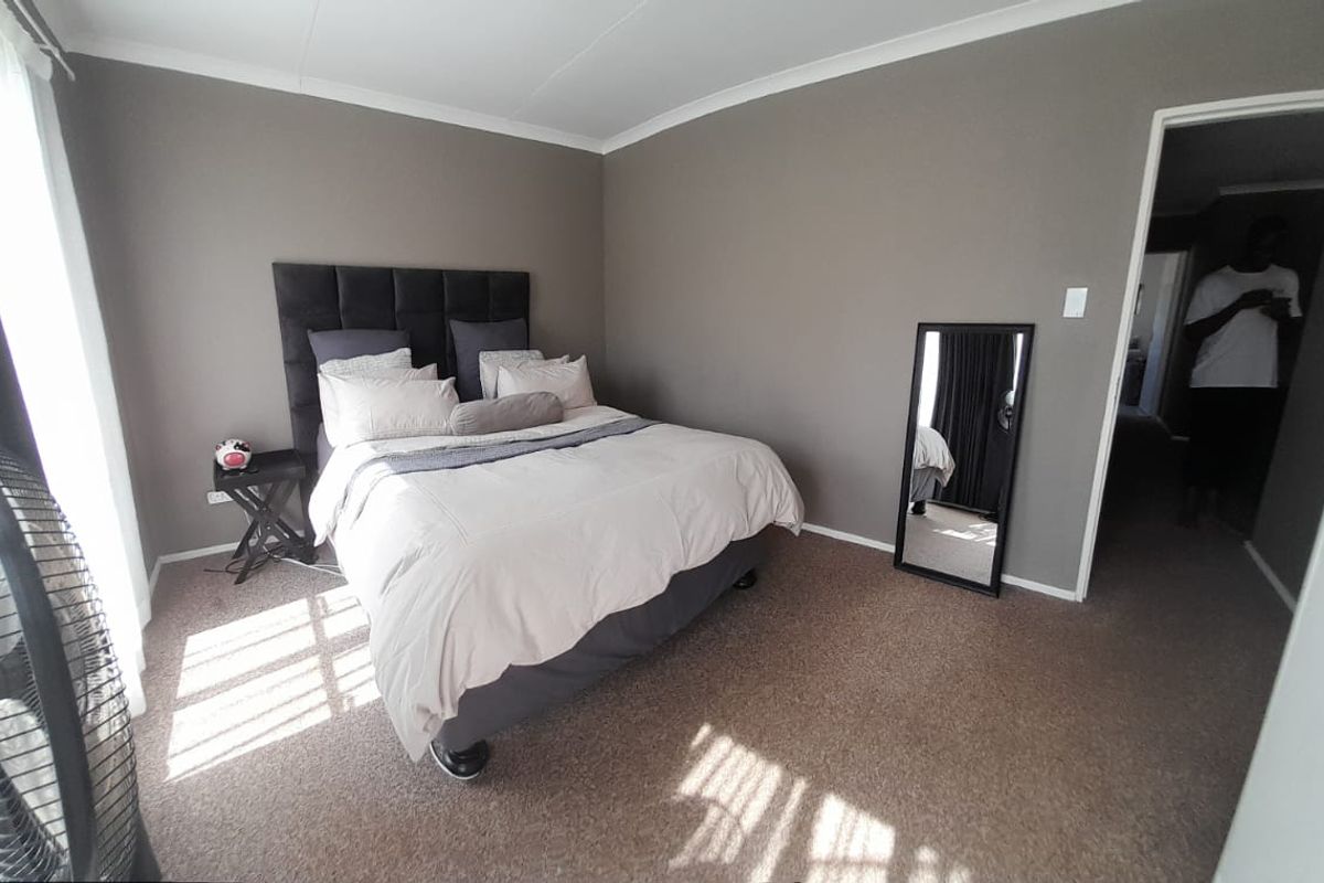 A neutrally painted bedroom featuring carpeted flooring and coved cornicing, offering a clean and functional space.