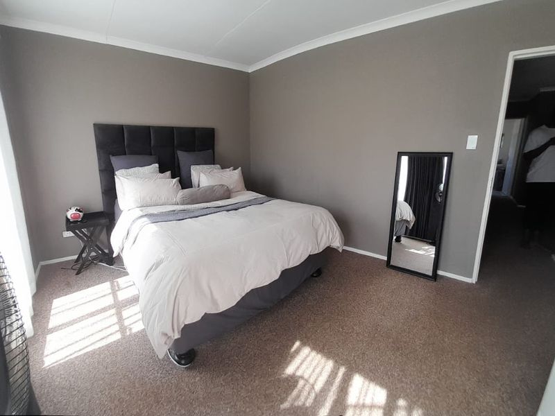 A neutrally painted bedroom featuring carpeted flooring and coved cornicing, offering a clean and functional space.