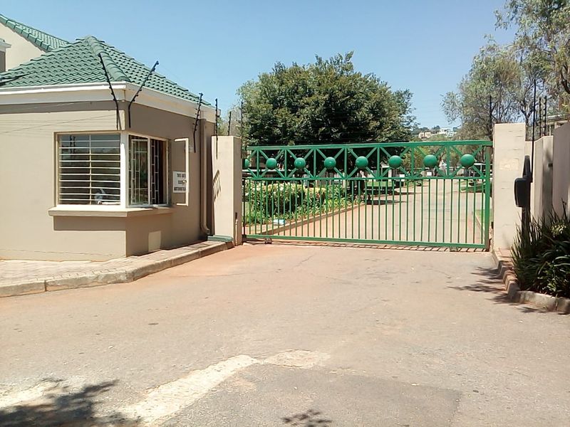 Secure gated entrance to the apartment complex featuring a guard house, automated security gate, and perimeter electric fencing.
