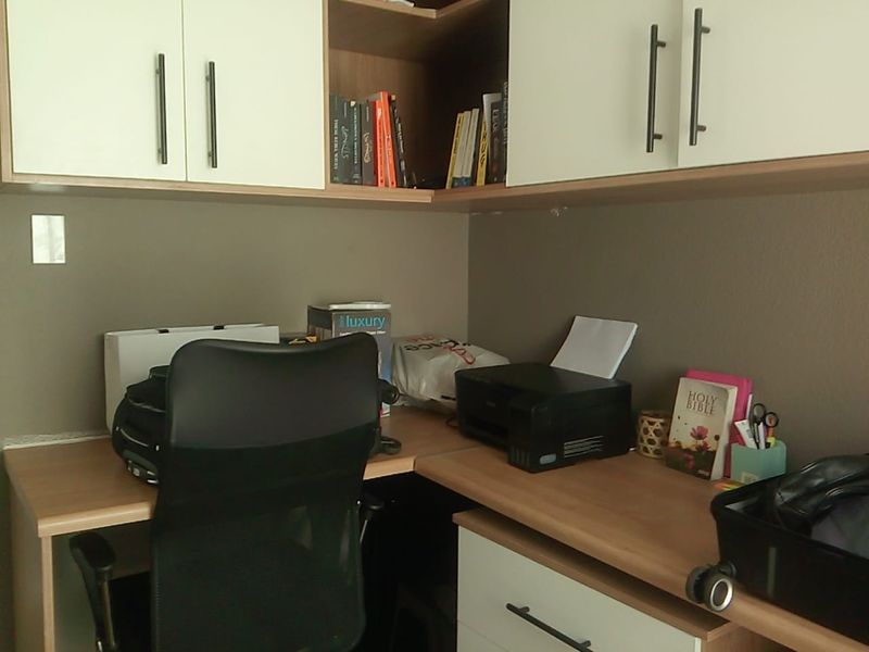 A functional home office space featuring built-in desk cabinetry and overhead storage units, providing a dedicated workspace within the apartment.