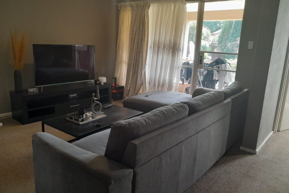 A living room featuring carpeted flooring and a large sliding glass door providing access to an outdoor area.