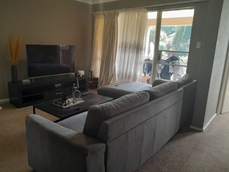 A living room featuring carpeted flooring and a large sliding glass door providing access to an outdoor area.