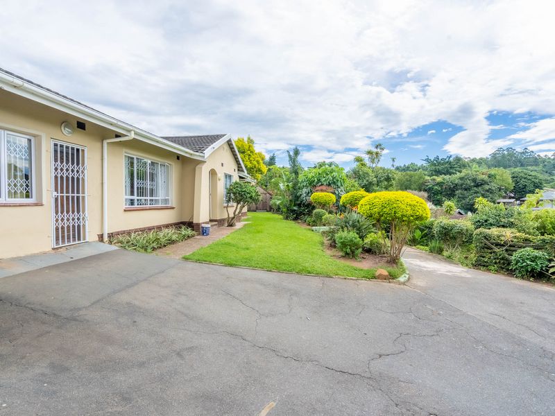 Front exterior view of the property featuring a paved driveway, security-fitted windows and doors, and a well-maintained garden area.