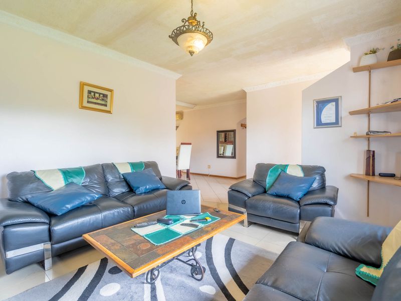 A living room featuring tiled flooring, built-in wall shelving, and decorative ceiling cornicing, offering a functional space with potential for cosmetic updates.