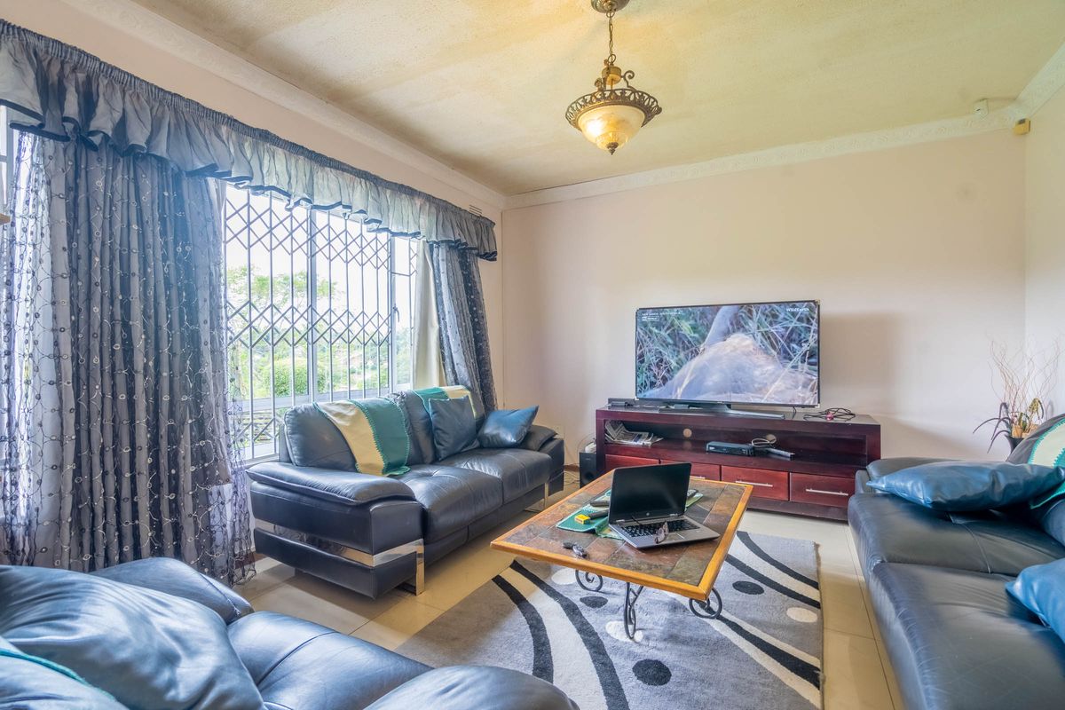 A living room featuring tiled flooring, decorative ceiling coving, and a security gate on the window.