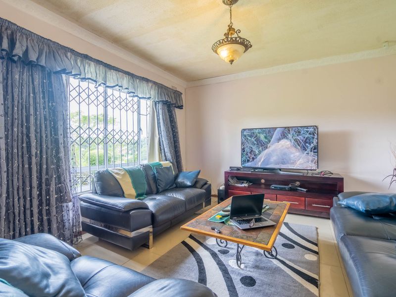 A living room featuring tiled flooring, decorative ceiling coving, and a security gate on the window.