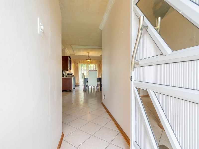 Entrance hallway featuring tiled flooring and a security gate, leading into an open-plan living and dining area.