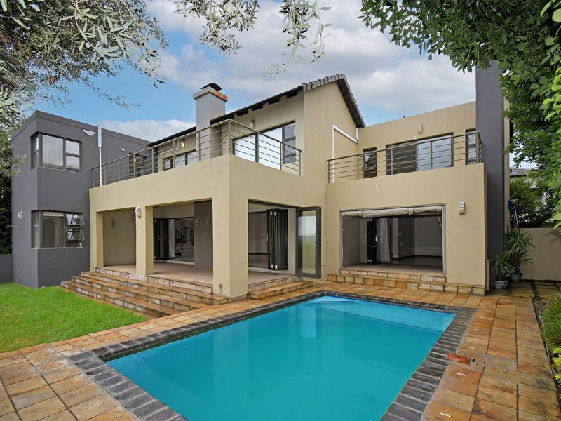 Rear view of a multi-level home featuring a swimming pool, covered patio area, and upper-level balconies with metal railings.
