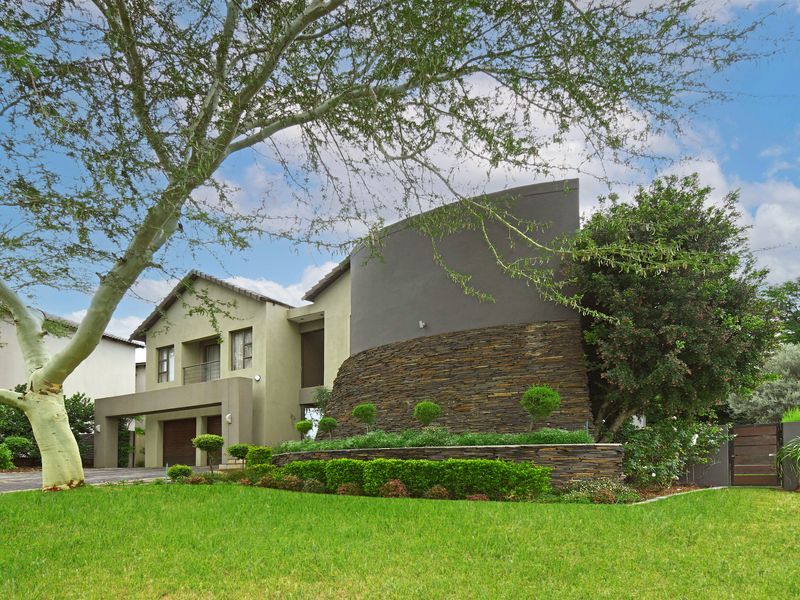 Modern double-storey residential facade featuring a curved stone-clad feature wall, manicured garden, and integrated garage.