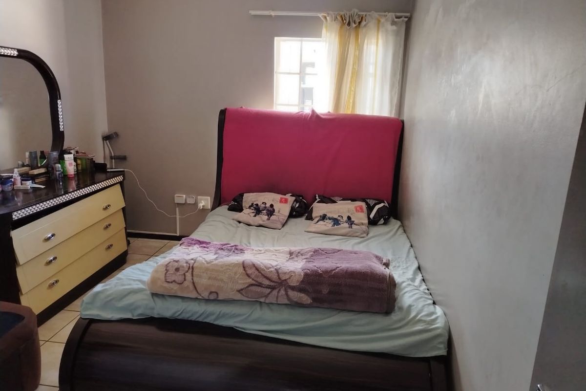 A standard bedroom featuring tiled flooring, a window with curtain rod, and neutral wall finishes.